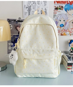 Detail of cream canvas backpack featuring yellow star patterns and a fluffy cloud charm