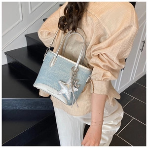 Détail d'un sac cabas en denim bleu clair avec garniture en cuir argenté porté par un mannequin