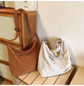 Close-up of tan and off-white waterproof nylon messenger bags with adjustable straps