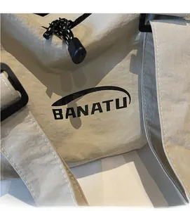 Close-up of beige canvas texture with black BANATU logo and adjustable strap detail