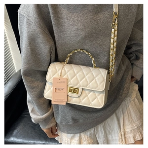 Detail showing white quilted leather chain bag with gold metal handle and turn-lock clasp