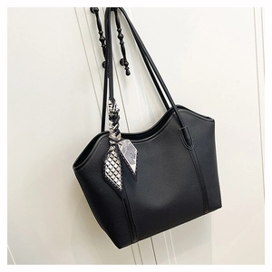 Detail of black lychee grain leather tote bag with geometric silk scarf on shoulder strap