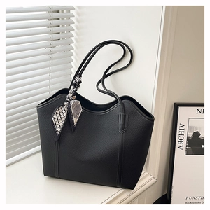 Close-up of black lychee grain leather tote bag featuring a decorative silk scarf detail
