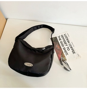 Macro shot of black nylon half-moon crossbody bag with branded logo and zipper detail