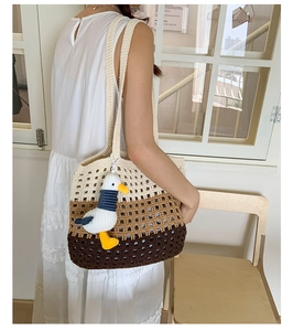 Detailed knit texture of a three-color striped crochet tote bag with a seagull charm