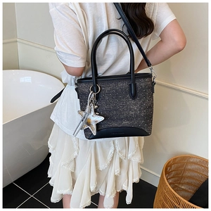 Détail d'un sac cabas à paillettes noires avec charm étoile argentée et base en cuir
