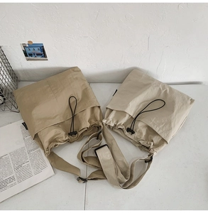 Macro view of nylon crossbody bucket bag showing drawstring pocket and metal buckle