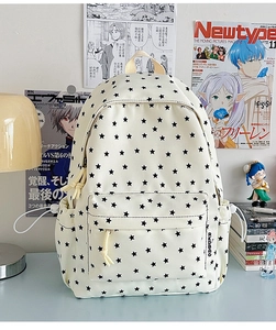 Close-up of white canvas backpack featuring black star patterns and multiple pockets