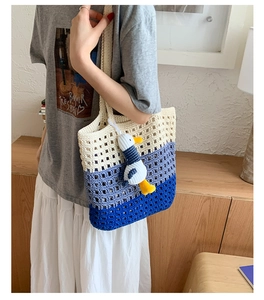 Detail of hand-woven crochet tote bag with gradient colors and plush seagull charm