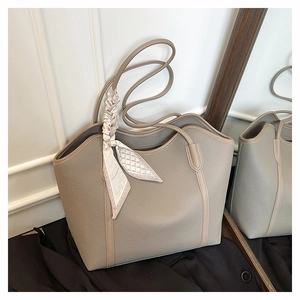 Detail view of taupe tote bag with lychee grain texture and decorative silk scarf