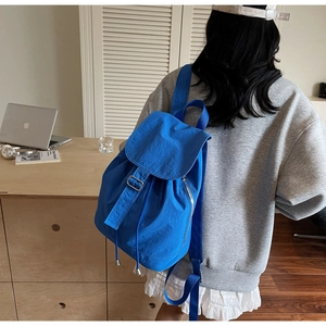Sac à dos bleu vif imperméable porté dans un décor de bureau à domicile minimaliste
