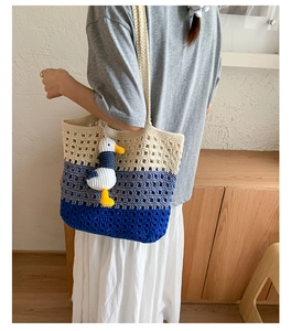 Close-up of tricolor crochet tote bag featuring hollow knit patterns and a cute duck pendant