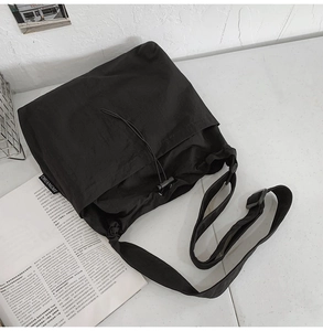 Detail of adjustable wide shoulder strap and drawstring closure on large nylon bucket bag
