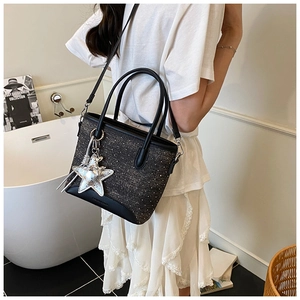 Détail d'un sac cabas en denim noir scintillant argenté avec un pendentif en forme d'étoile