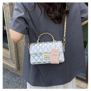 Detail of silver quilted crossbody bag with gold metal handle and square twist lock