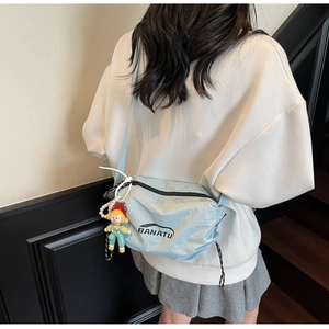 Detail of light blue nylon crossbody bag featuring BANATU logo and cartoon boy pendant