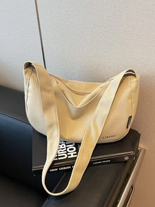 Schicke beige Segeltuch-Halbmond-Umhängetasche mit breitem Gurt auf Lederfläche