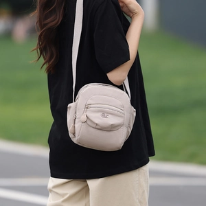 Vue détaillée du sac bandoulière en nylon abricot avec sangle réglable et logo en métal