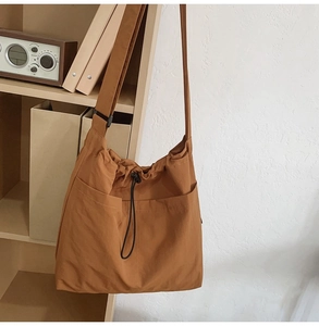 Detail of caramel nylon bucket bag with drawstring closure and large front pockets