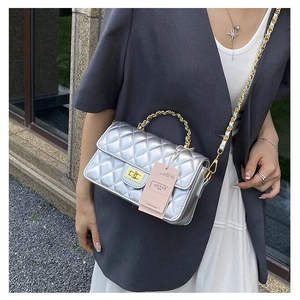 Detail of silver quilted crossbody bag with golden chain strap and rotary lock