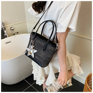 Détail d'un sac seau gris foncé avec étoile à paillettes et bandoulière porté par un modèle