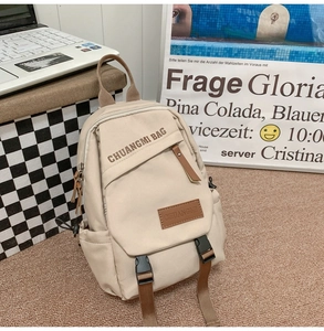 Detail view of cream canvas crossbody bag with brown straps and buckle decoration