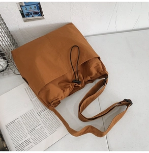 Close-up of caramel nylon bag featuring drawstring closure and textured side pockets