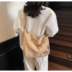 Détail du sac cabas en toile beige avec bandoulière réglable et étiquette de marque