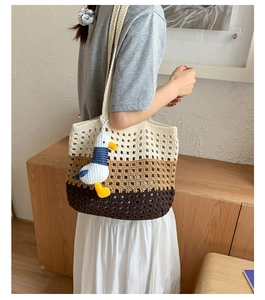 Detail of hand-crocheted hollow tote bag with gradient stripes and seagull charm accessory