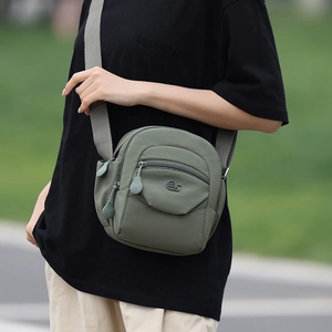 Détail d'un sac bandoulière en nylon vert armée avec design multi-poches et sangle grise