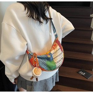 Dettaglio di una borsa hobo patchwork retrò con ciondolo a cuore indossata sulle scale