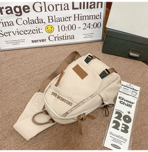 Detail of beige canvas crossbody bag with adjustable strap and multiple zip compartments