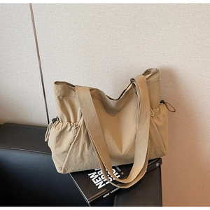 Detail of khaki nylon tote bag with drawstring accents on a leather sofa