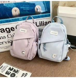 Detail of lavender and light blue nylon crossbody bags with logo patches and zippers