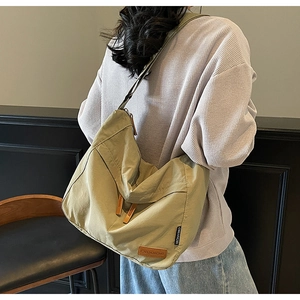 Détail arrière d'un grand sac bandoulière réglable en nylon vert olive sur modèle