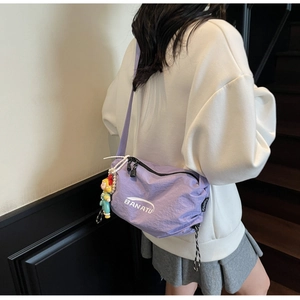 Lavender nylon crossbody bag detail with white brand logo and colorful girl doll charm