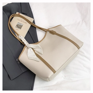 Close-up of cream pebble leather tote bag with brown straps and decorative silk scarf