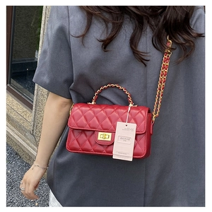 Detail of red quilted crossbody bag with gold chain strap and elegant turn-lock closure