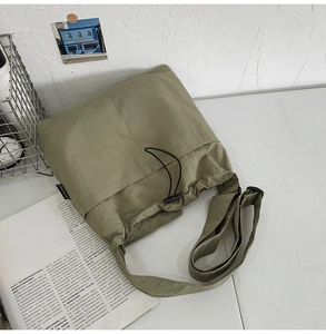 Detail of olive green nylon crossbody bag showing the unique drawstring texture and wide strap