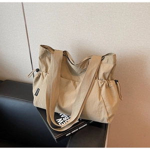 Detail of khaki nylon tote bag featuring adjustable drawstring sides and wide woven strap