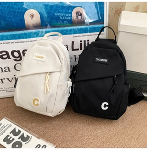 Detail of minimalist nylon chest bags in black and beige with brand patch and zip pullers