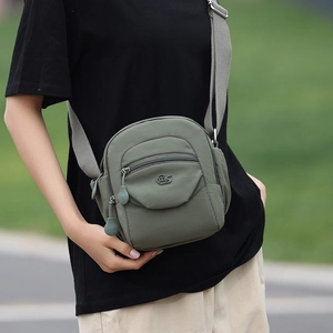 Détail du sac à bandoulière en nylon vert olive avec sangle grise et poches zippées pratiques