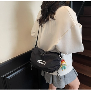 Detail view of a black nylon banana crossbody bag with BANATU logo and cute charm