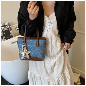 Détail du sac seau en denim avec garniture en cuir marron et pendentif étoile