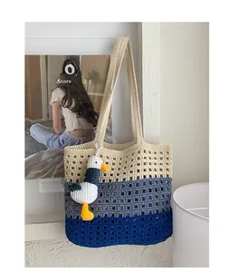 Detail view of a hand-knitted tote bag with gradient colors and seagull charm