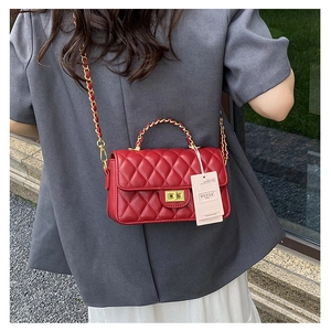 Detailed view of a red quilted leather chain bag worn as a crossbody on a model