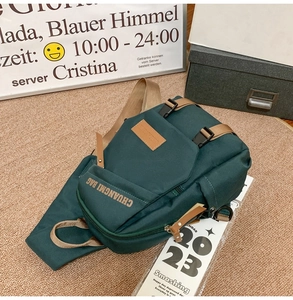 Detail view of dark green nylon crossbody bag with adjustable khaki strap on textured rug