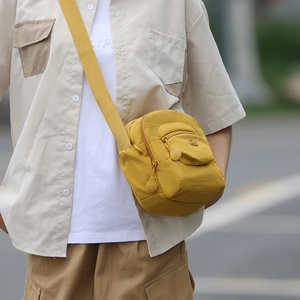 Détail du sac bandoulière en nylon jaune moutarde avec double zip et logo en relief