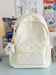 Cream canvas backpack with pink star prints and a plush star charm in a lifestyle setting
