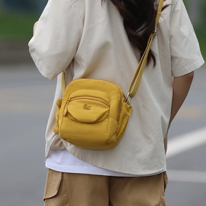 Photo en extérieur du sac bandoulière en nylon jaune vif avec sangle réglable sur modèle